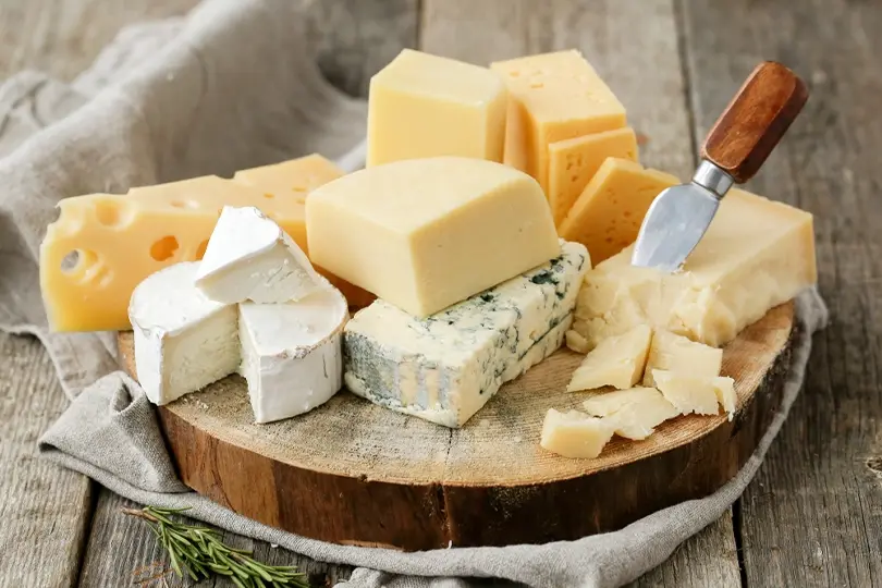 A delicious assortment of cheeses on a rustic wooden board.